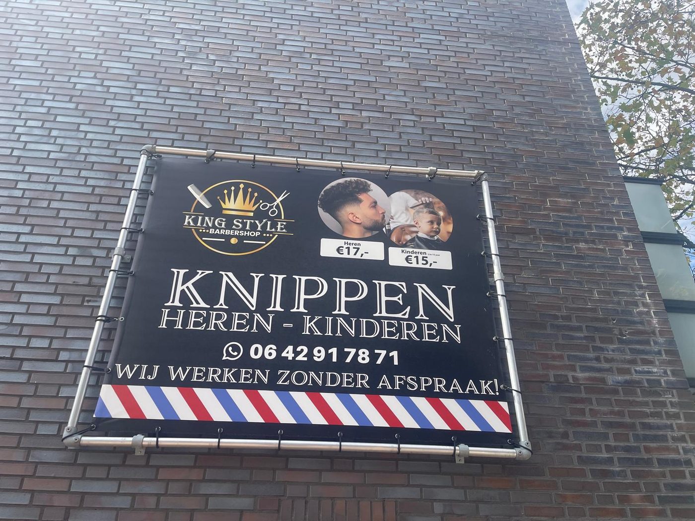 Het spandoek aan de gevel: knippen voor heren en kinderen, wij werken zonder afspraak